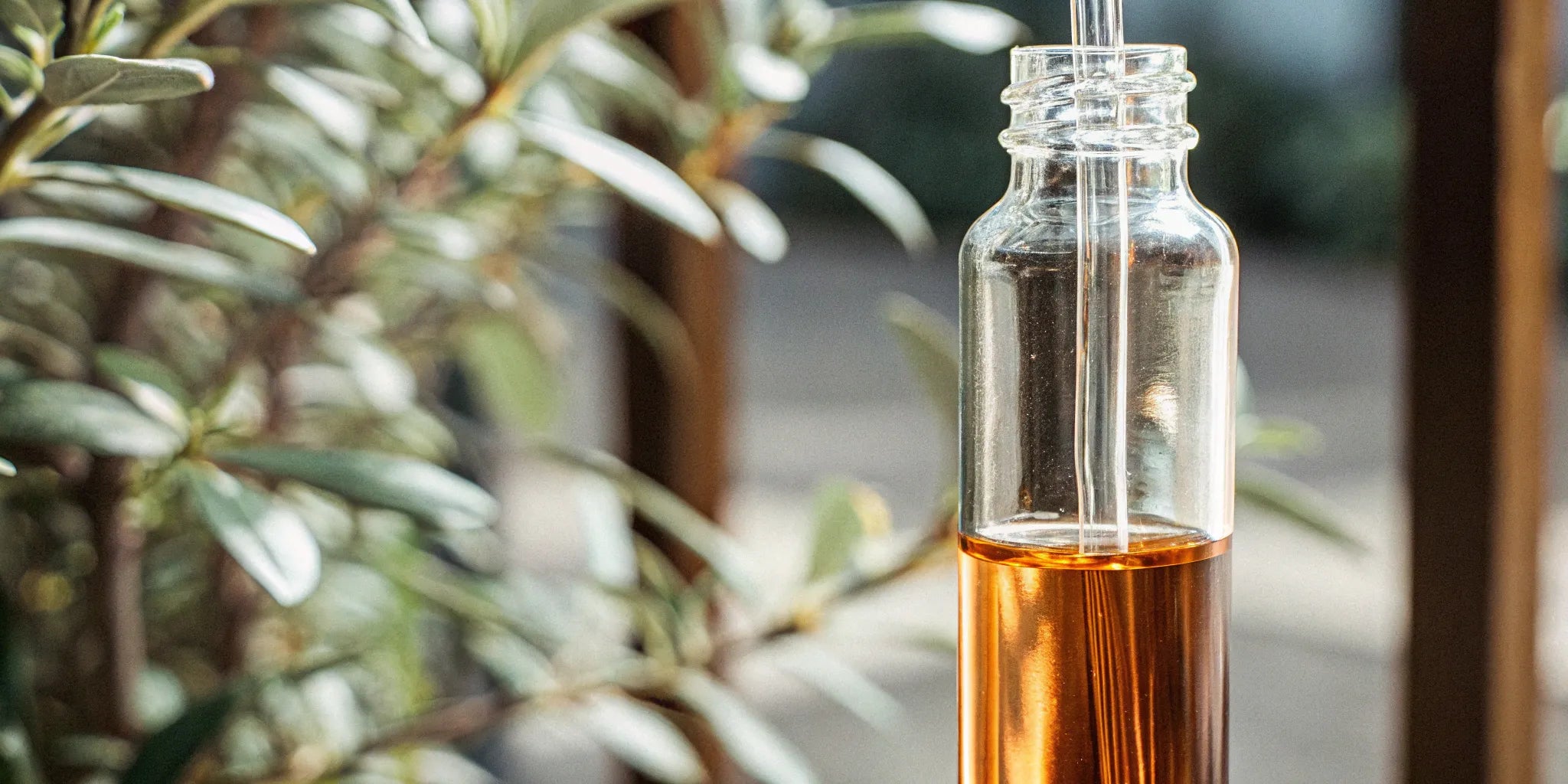 A glass dropper bottle of amber delta 10 distillate surrounded by hemp leaves.