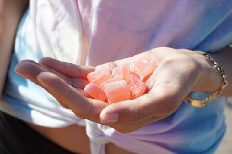 A hand holding several pink Delta-9 THC gummies