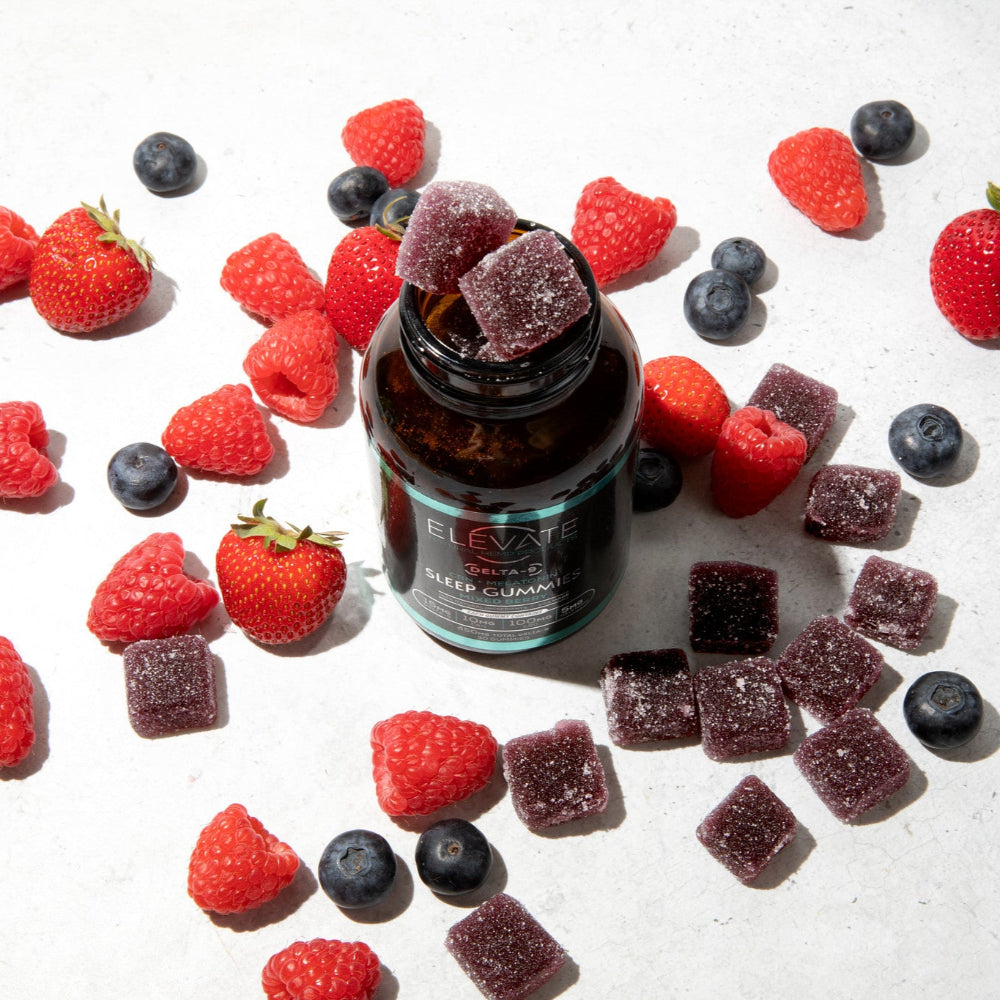 Bottle of Elevate Gummies surrounded by fresh berries on a light surface