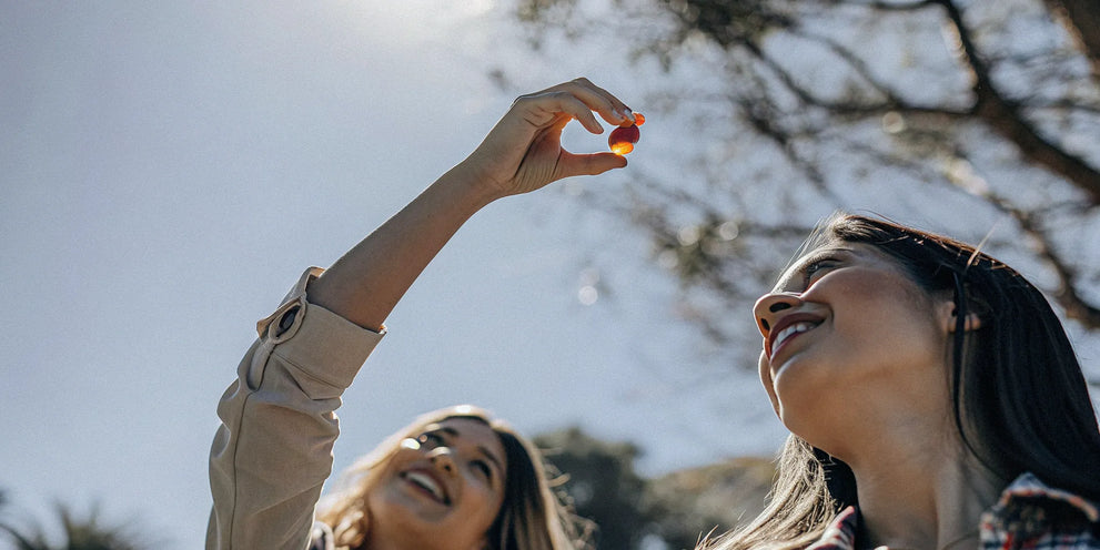 Two women smiling, holding up the best HHC gummies for energy and focus.