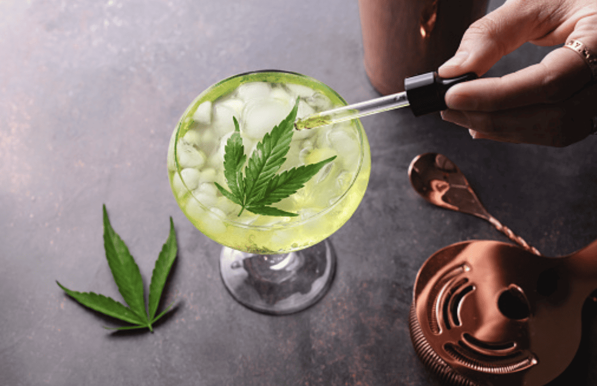A cocktail with a dropper and cannabis leaves, suggesting a mix of Delta 8 and alcohol.