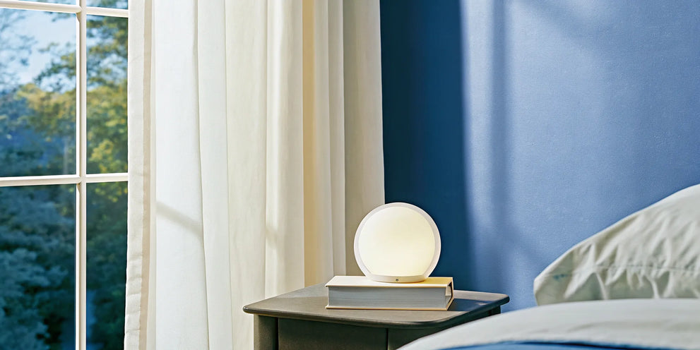 A bottle of CBD melatonin gummies for sleep on a nightstand beside a bed.