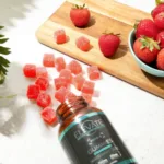 Bottle of 'Elevate' gummies with strawberries and gummy bears on a wooden board.
