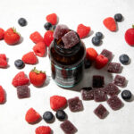 Bottle of Elevate Gummies surrounded by fresh berries on a light surface