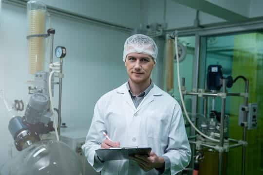 A scientist in a lab coat holding a clipboard in a laboratory, emphasizing research and quality assurance.
